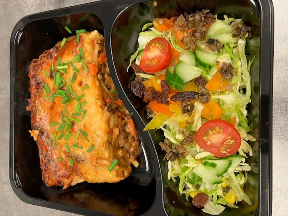 en platikbakke med lasagne og salat