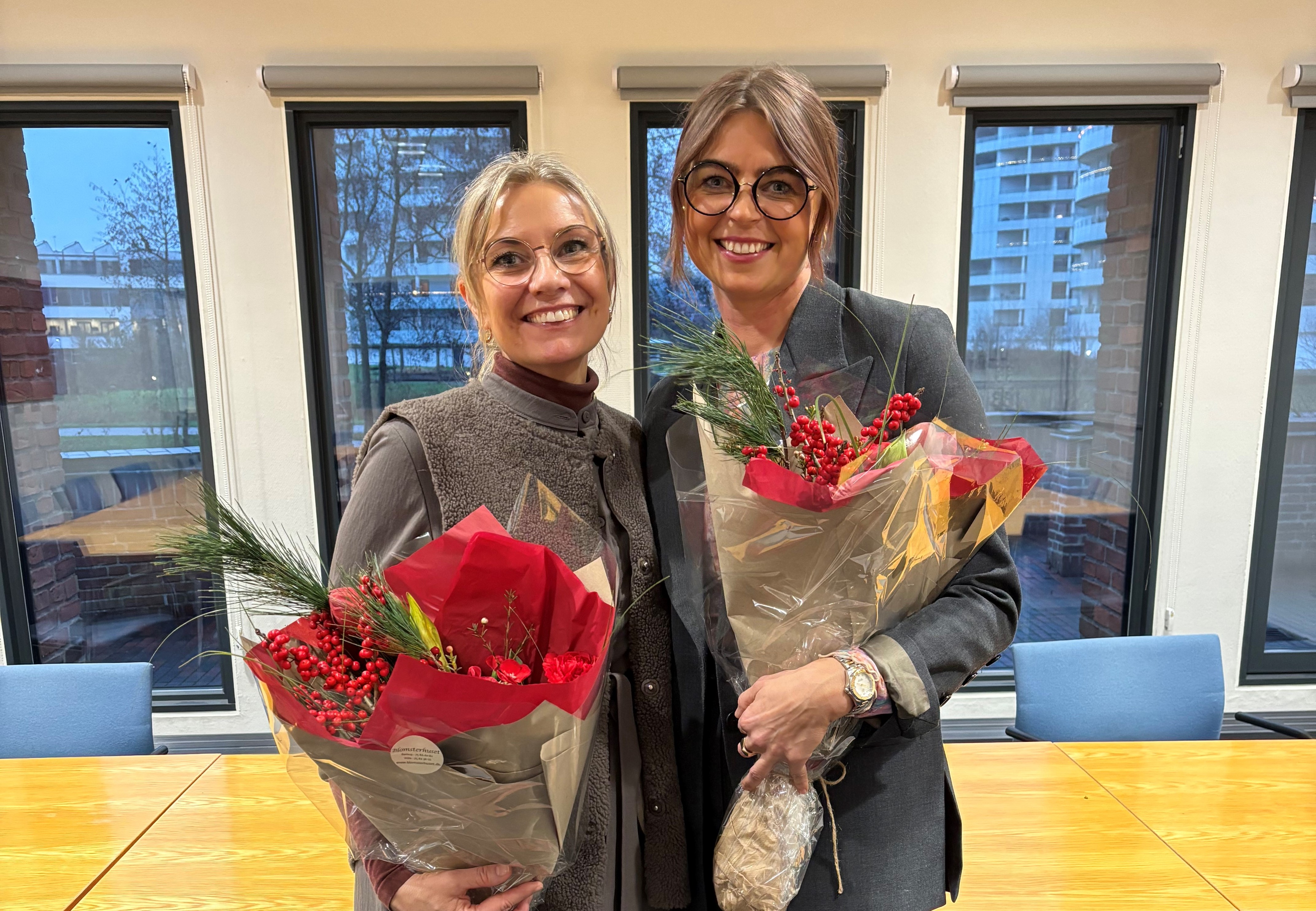 To kvindelige forskere står med hver deres buket blomster