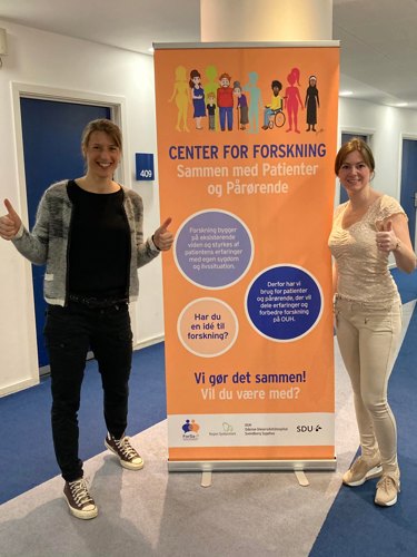 Forskningsleder Astrid Janssens og patient- og pårørendeleder Janni Eriksen-Jensen med forskningscentrets banner