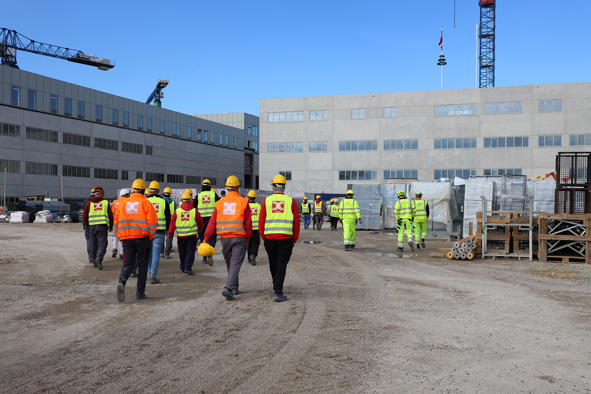 Håndværkere går mod hovedindgangen på det nye OUH i forbindelse med rejsegilde