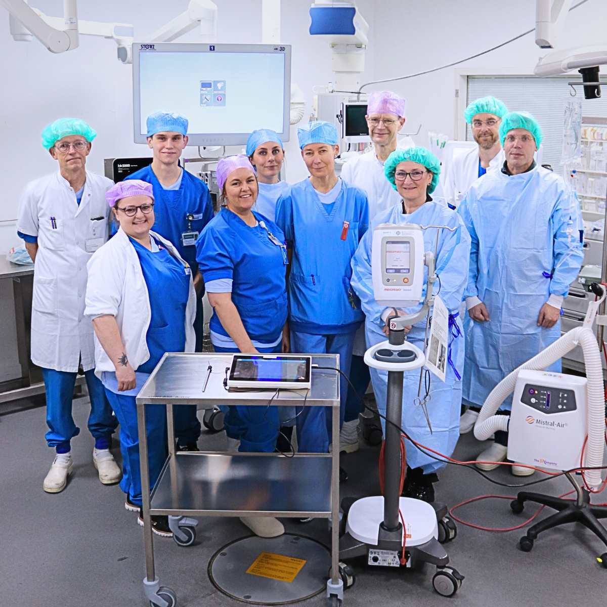 klinikere i blåt og hvidt  operationstøj står i OP og kigger  mod kamera
