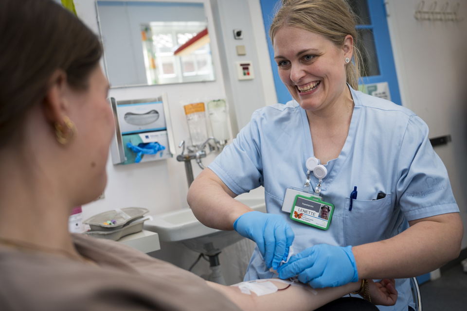 Sygeplejerske tager blodprøve fra kvindelig patient.
